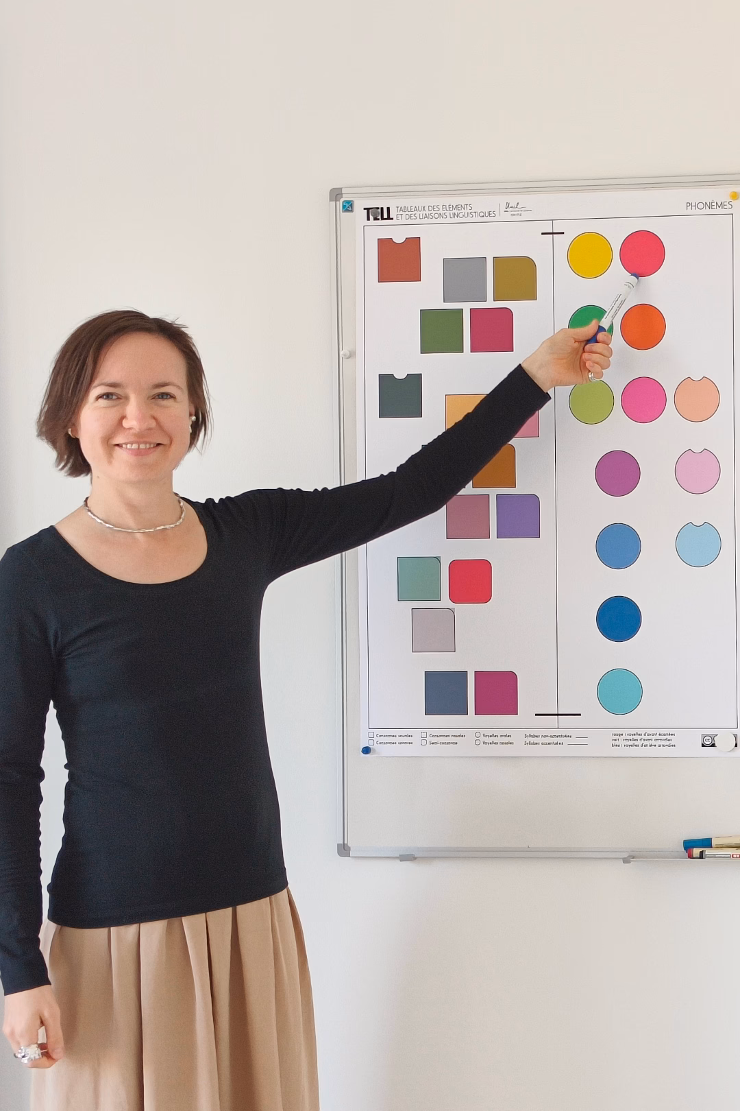 Une formatrice souriante utilise la CLEF des phonèmes de Phonocolor pour enseigner le français.