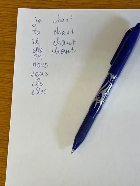 Feuille où l'élève a commencé à écrire la conjugaison de chanter. Tous les pronoms sont écrits et on retrouve la racine "chant", mais pas de terminaisons.