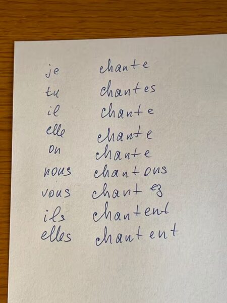 Feuille avec la conjugaison du verbe chanter au présent de l'indicatif, écrite à la main