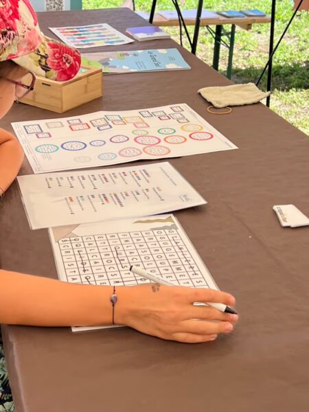 Une jeune fille est concentrée sur un escape game à imprimer avec des mts cachés, des définitions et des ronds-carrés de couleur